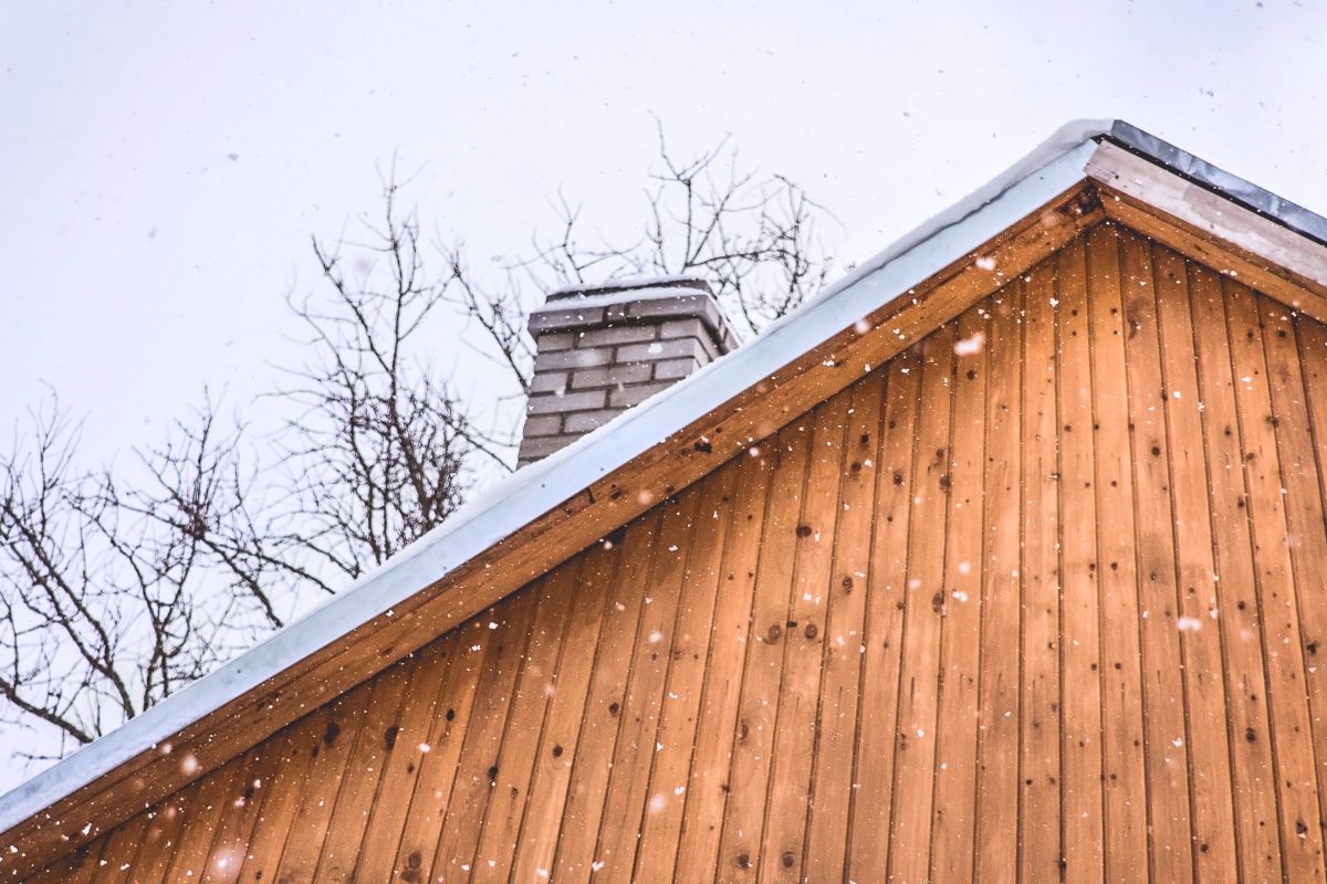 Snowfall over a wooden roof. Winter day.