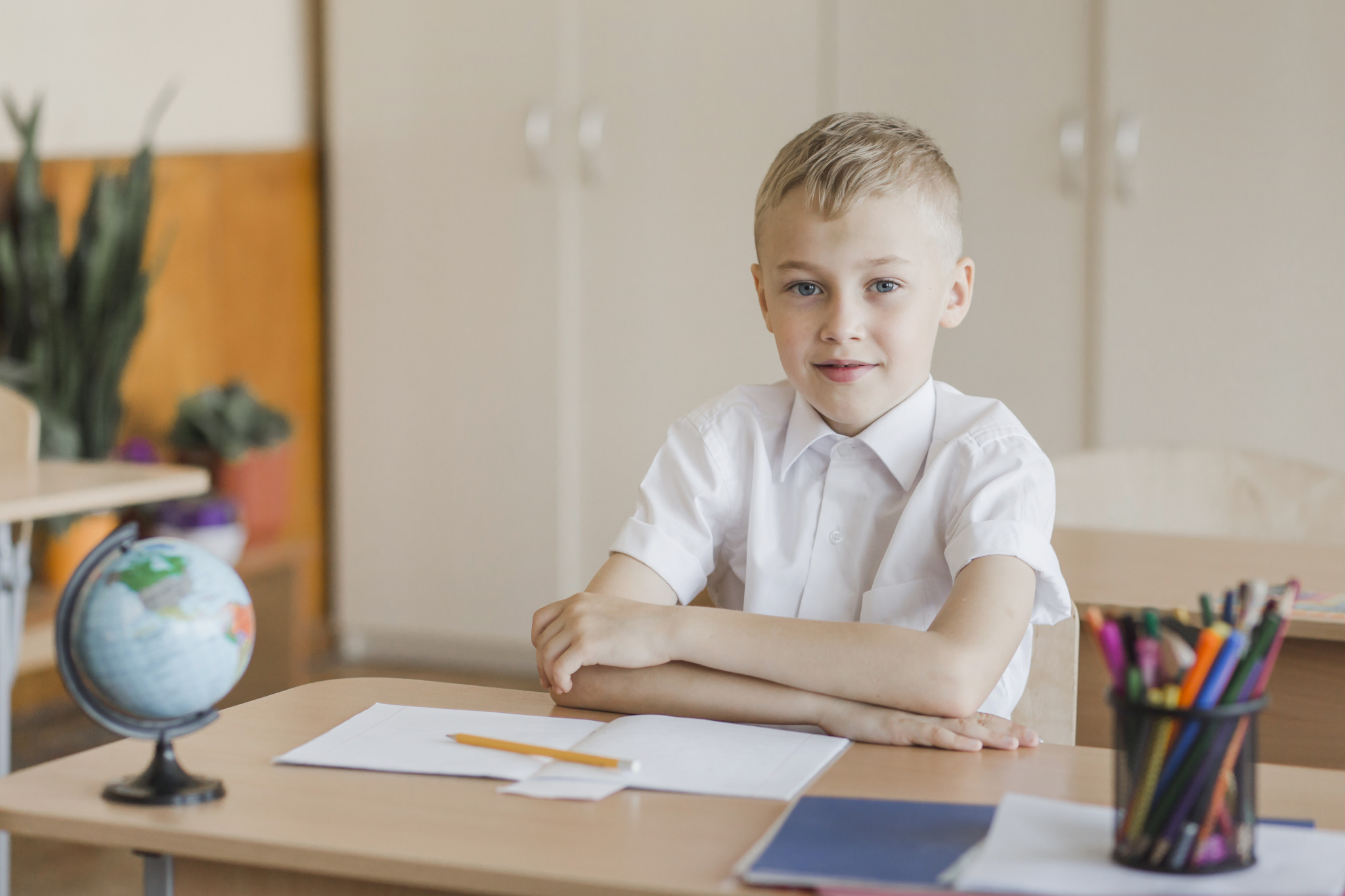 boy-sitting-with-hands-table-classroom